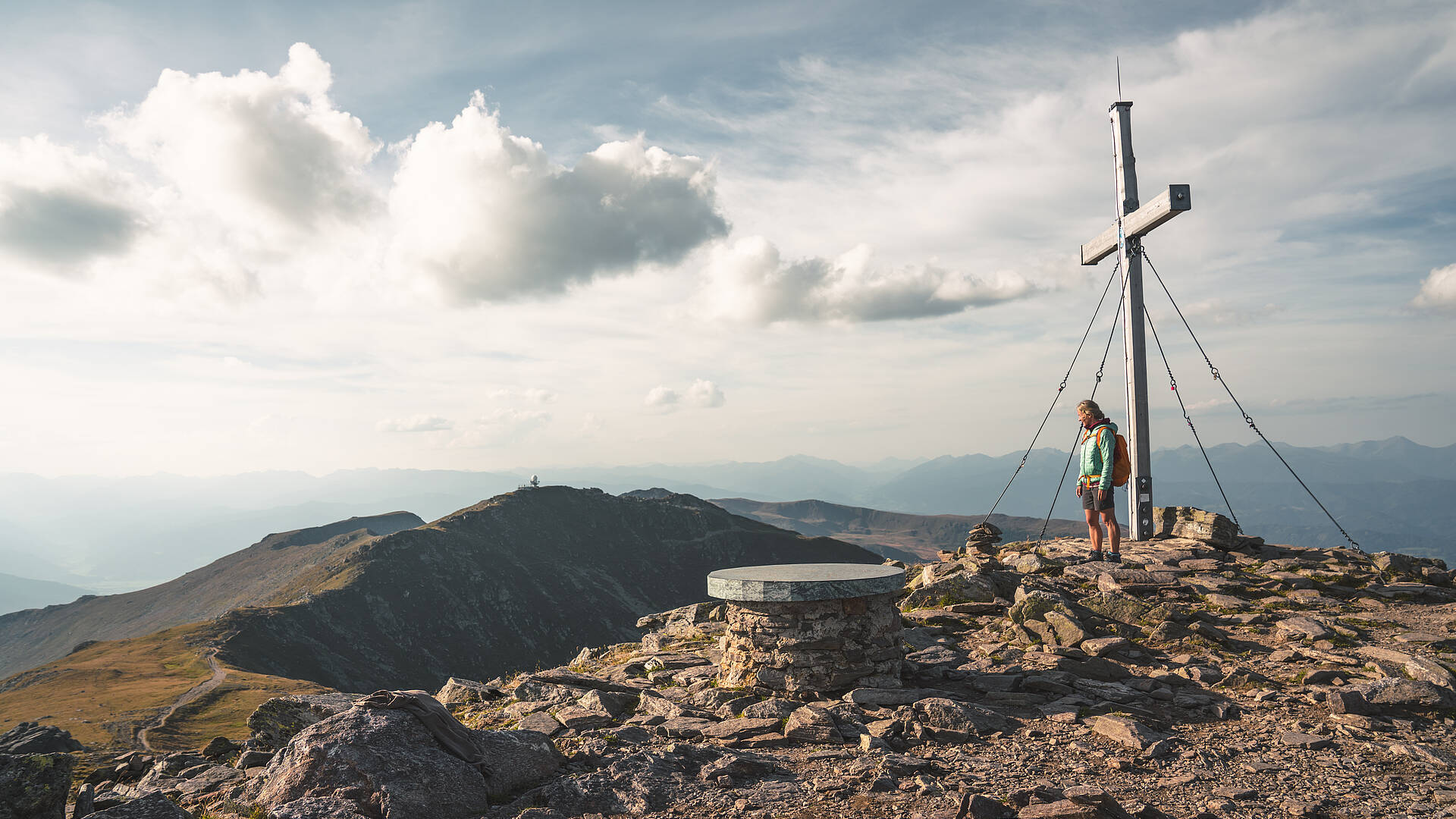 Frau beim Gipfelkreuz beim Panoramaweg Suedalpen Etappe-20 Zirbitzkogel